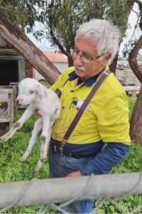Peter on his property holding a lamb.
