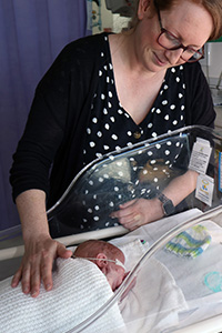 A mother looks at her small newborn son.