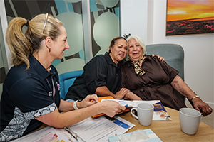 A female health professional sits talking with two women