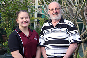 A female occupational therapist stands next to male patient Joseph Kelly-Seymour in a garden