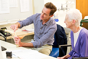 A doctor using a model of a body joint to explain a surgical procedure to woman