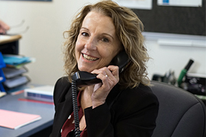 A woman holds a telephone against her ear while in conversation