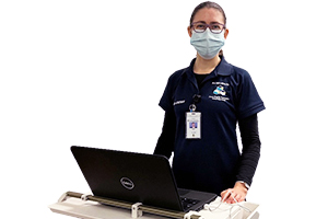 A female menu assistant stands in front of a computer on a moveable workstation