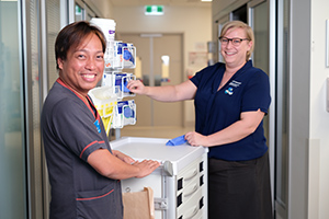 A male and female neonatal nurse stand loading medical supplies into an equipment trolley