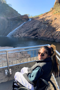 Stung pictured bottom right, sitting in a wheelchair with Serpentine Falls in the background. 