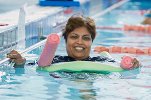 A woman using two pool noodles for suport in a swimming pool