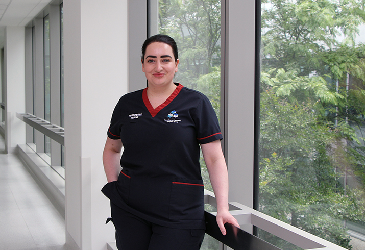 A female nurse stands in a hospital corridor in front of a window