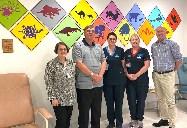 Peter Lowe pictured second from left standing infront of his paintings with four staff from Fiona Stanley Hospital.