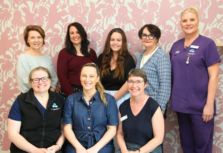 Eight members of the FSH ‘Making the Changes’ maternity working group pictured together in front of a pink, floral wall.