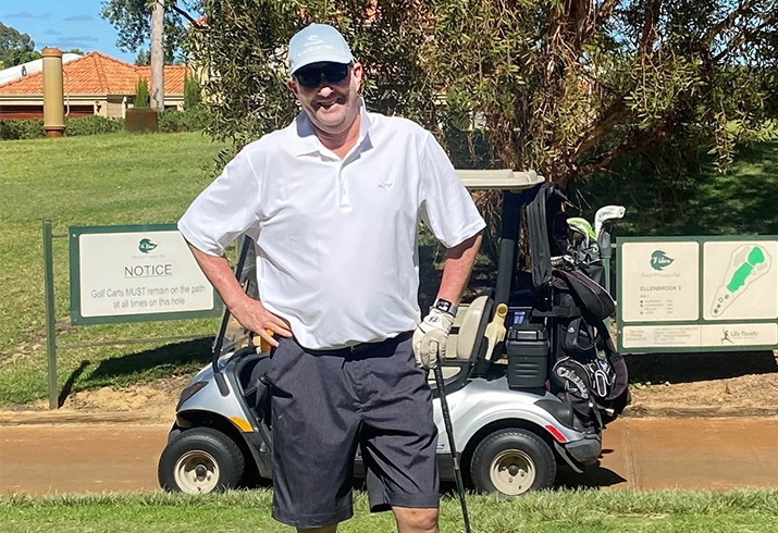 Alastair Hay standing on the golfing green when a golf buggy in the background. 