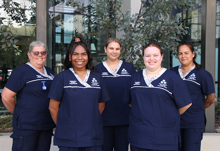 Five female Aboriginal Health Practitioners, standing together wearing navy blue scrubs.