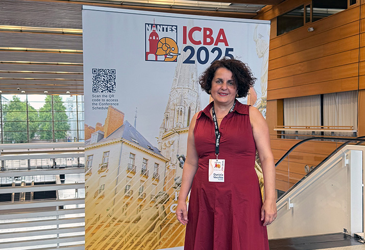 Daniela Vecchio stands in front of a conference banner that reads ICBA 2025 Nantes