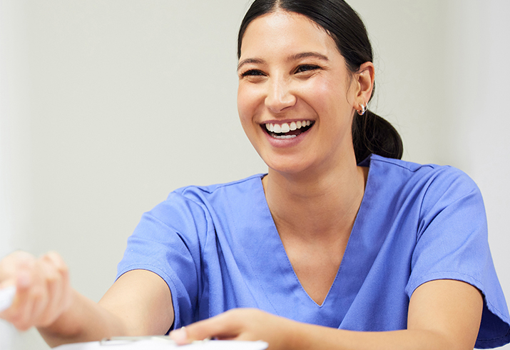A female nurse hands over a folder to a person off camera