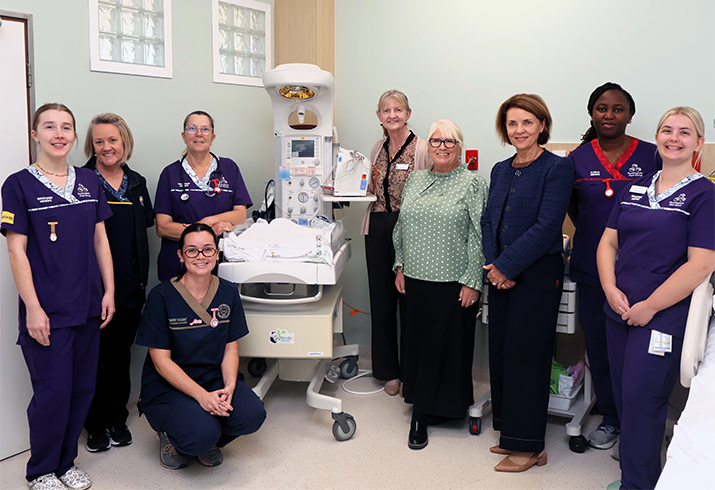 Nine midwives from South Metropolitan Health Service stand together around a piece of neonatal equipment